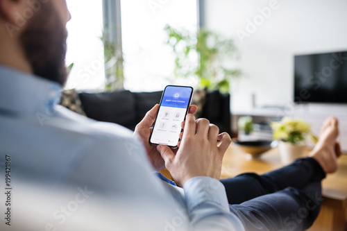 A man holding a smartphone with smart home screen. photo