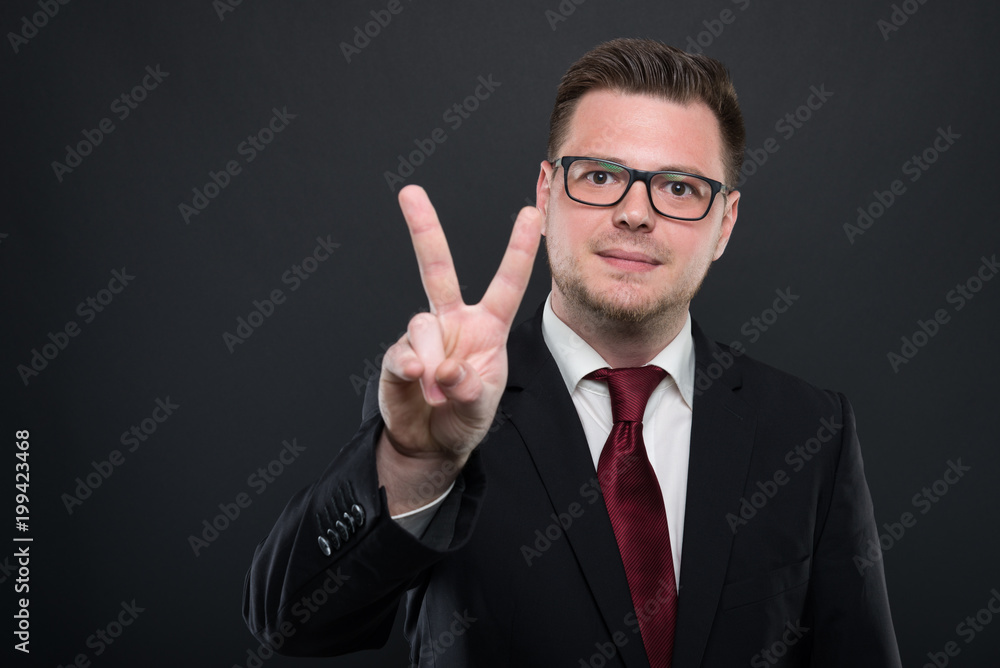 Portrait of business man wearing black suit showing peace gesture. Portrait of business man wearing black suit showing peace gesture.