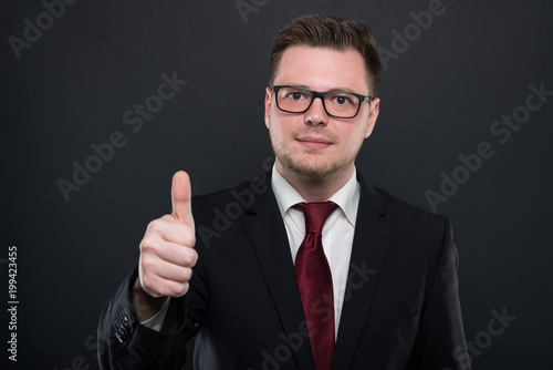 Portrait of business man wearing black suit showing like gesture.