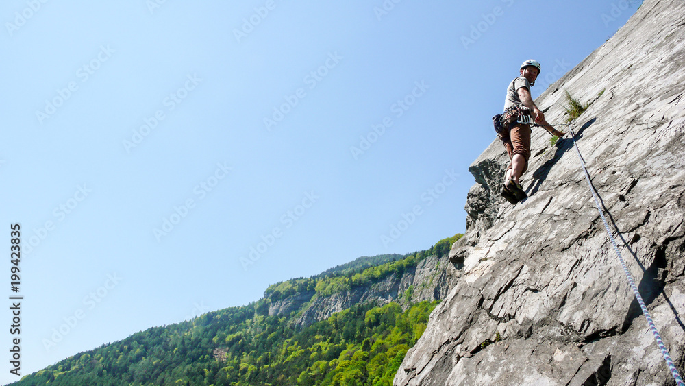 mountain guide rock climber on a slab limestone climbing route in the Alps of Switzerland on a beautiful day