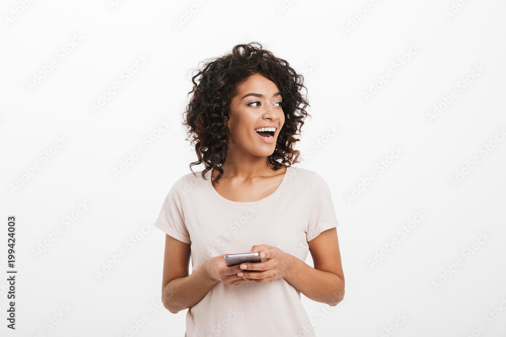 Communicating woman with afro hairstyle using mobile phone and looking aside on copyspace, isolated over white background Communicating woman with afro hairstyle using mobile phone and looking aside on copyspace, isolated over white background