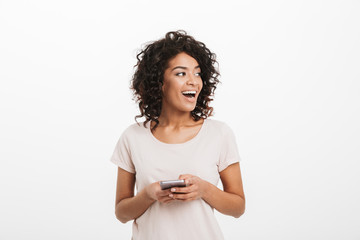 Communicating woman with afro hairstyle using mobile phone and looking aside on copyspace, isolated over white background