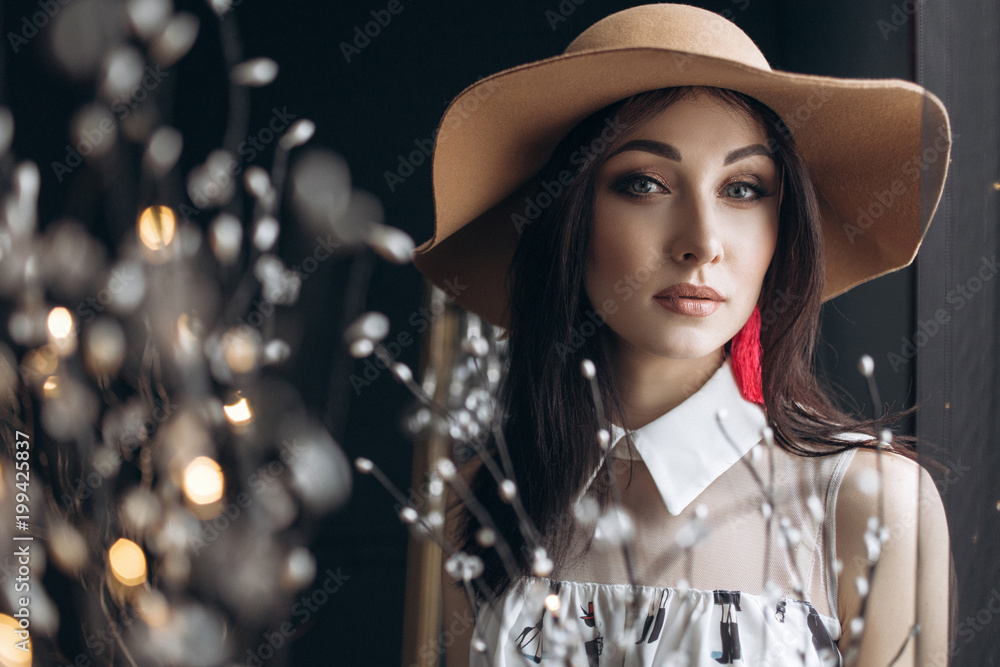 Adorable woman in beige hat and with fashion look poses in the dark studio Adorable woman in beige hat and with fashion look poses in the dark studio