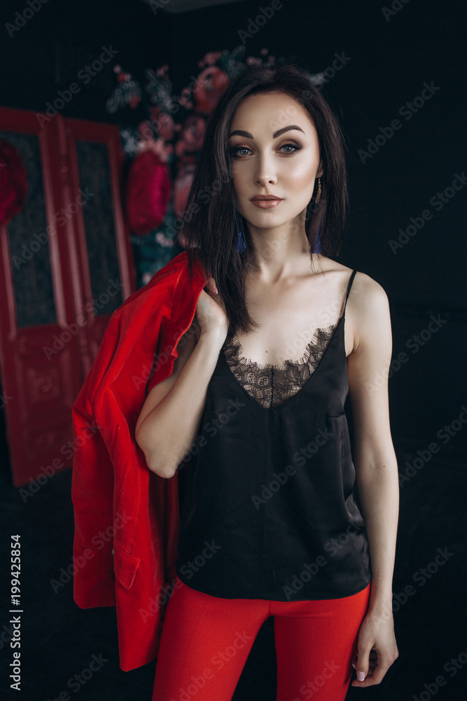 Fototapeta premium Woman in red suit stands before colorful flowers