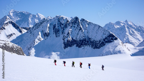 group of backcountry skiers crossing a glacier on their way to a high summit in the Alps