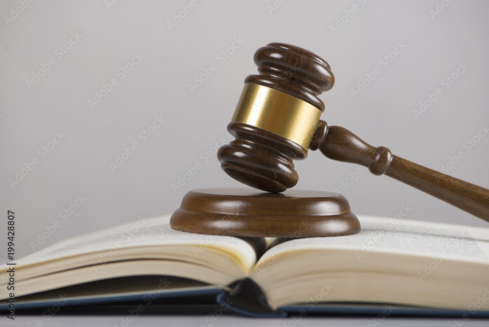 Wooden mallet used by a judge or at an auction next to a book. Concept Wooden mallet used by a judge or at an auction next to a book. Concept