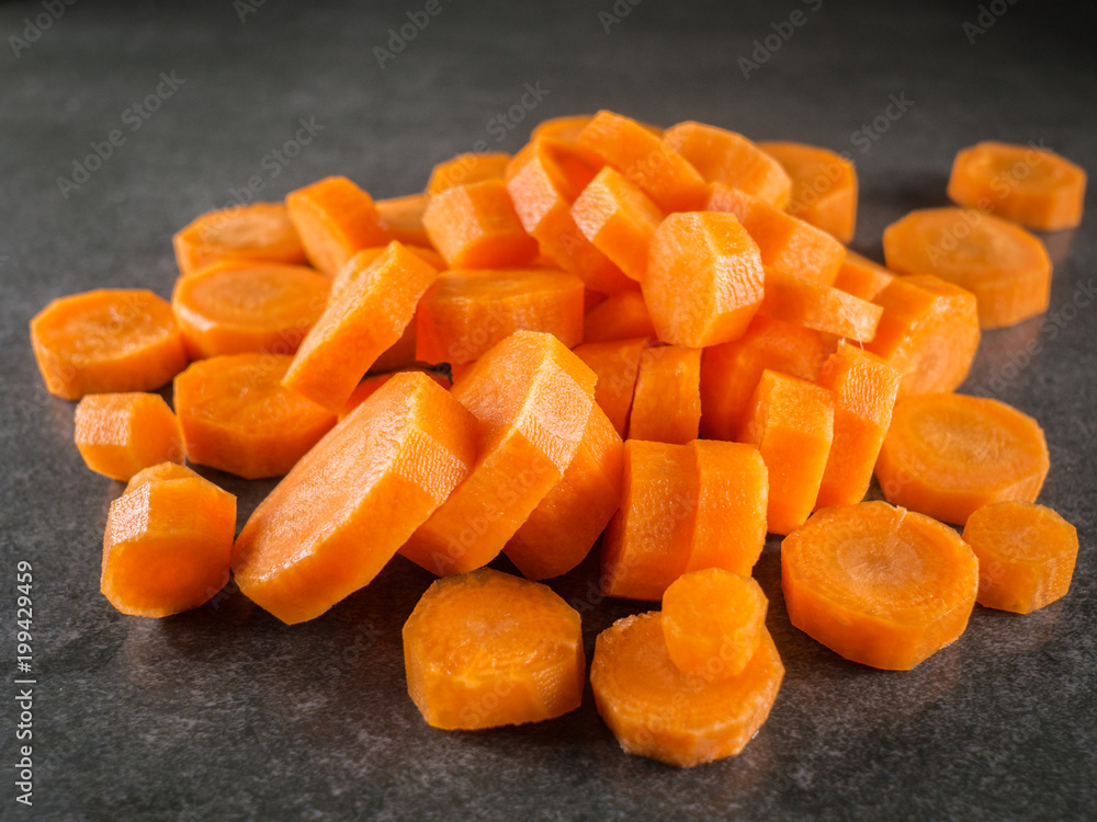 Pile of carrot slice over dark gray marble background. Pile of carrot slice over dark gray marble background.