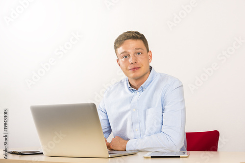 Office worker using computer on table, male caucasian young.