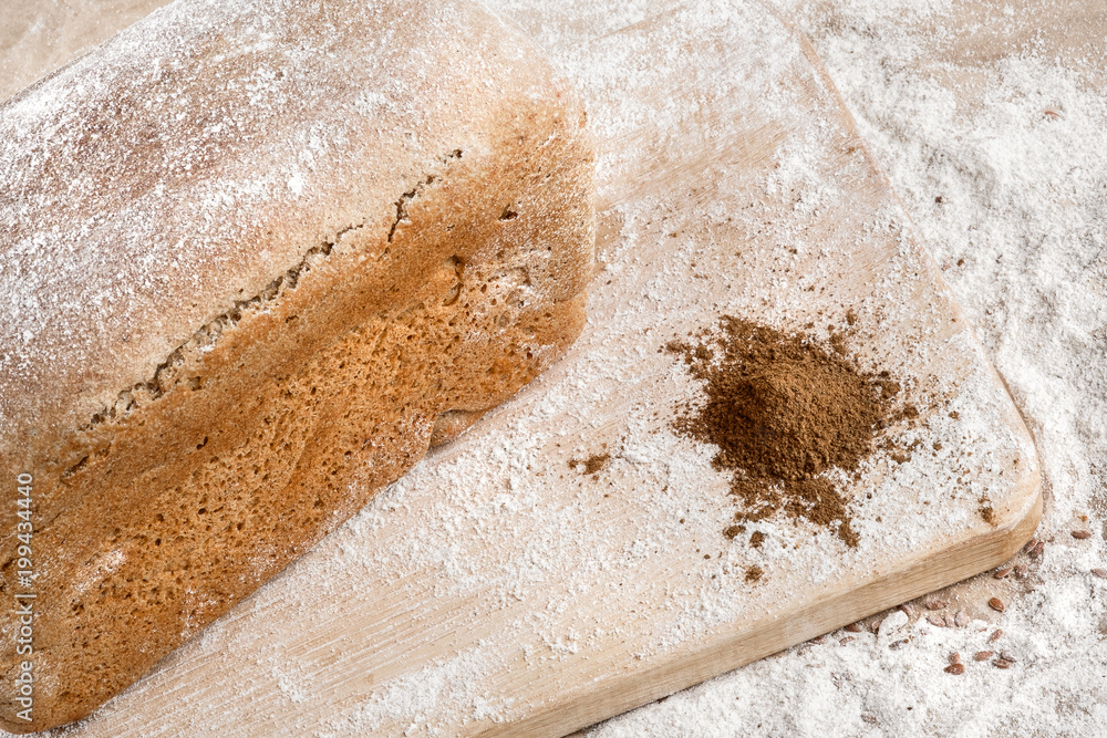 Rye bread on malt and flour, lies on the table. Near a pinch of flour and malt.