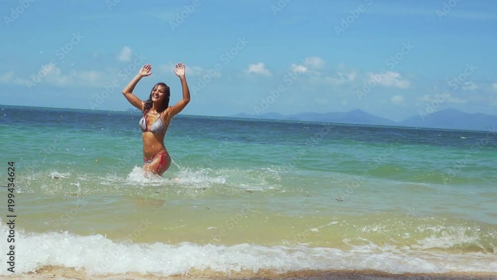 Joyful young woman in bikini running along the exotic beach swimming in the sea on sunny summer day. slow motion. 1920x1080 Joyful young woman in bikini running along the exotic beach swimming in the sea on sunny summer day. slow motion. 1920x1080