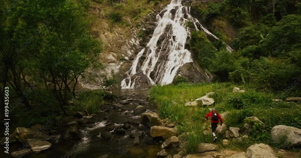 traveler trekking to big and beautiful waterfall in tropical rainforest traveler trekking to big and beautiful waterfall in tropical rainforest