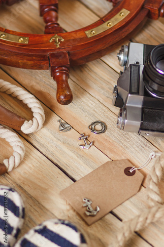 Striped slippers, camera, bag and maritime decorations on the wooden background