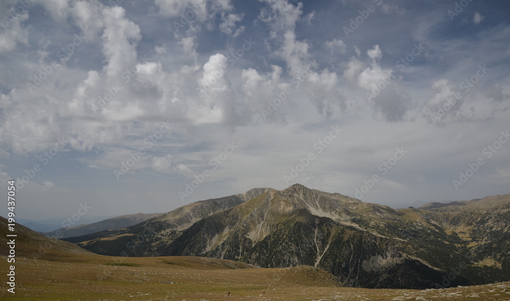Two hikers on a green meadow in the mountains Two hikers on a green meadow in the mountains