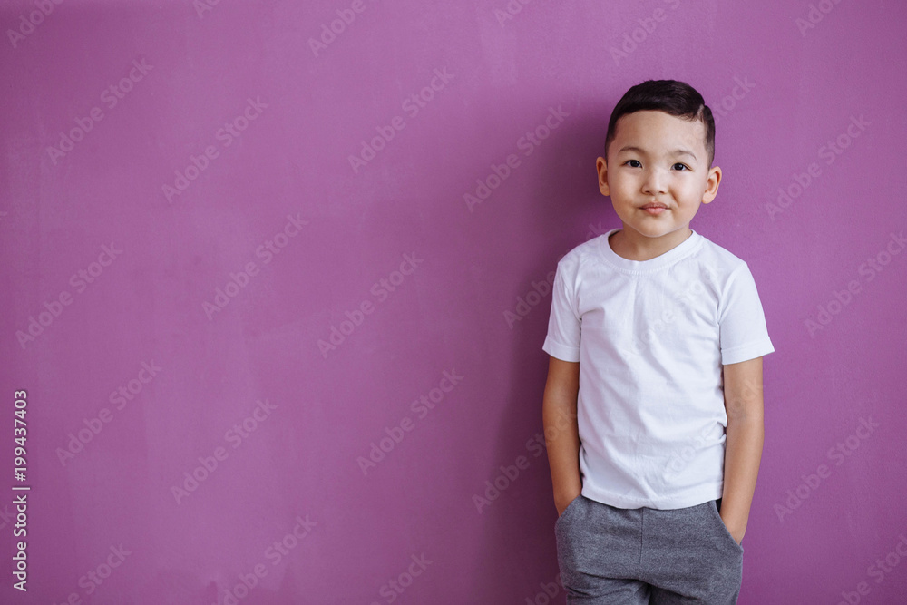 the child is standing in a white T-shirt on a lilac background. Mock up. the child is standing in a white T-shirt on a lilac background. Mock up.