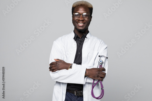 Portrait of handsome Afro American doctor with sthethoscope in white coat looking at camera, isolated on gray background photo