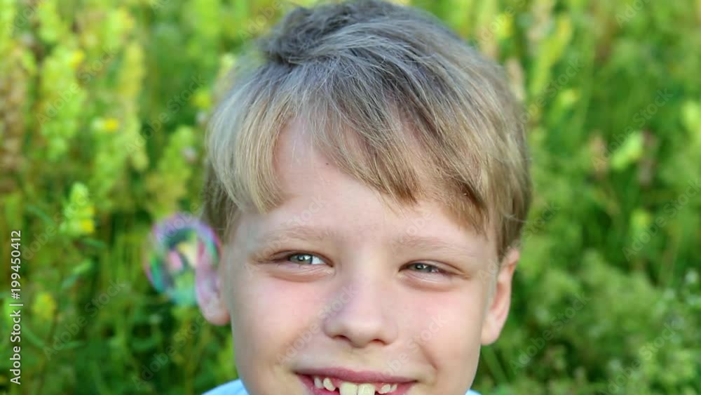 Closeup portrait of cute handsome little boy sitting in green grassy meadow catching soap baubles with hands and tongue. Summer fun concept. Closeup portrait of cute handsome little boy sitting in green grassy meadow catching soap baubles with hands and tongue. Summer fun concept.