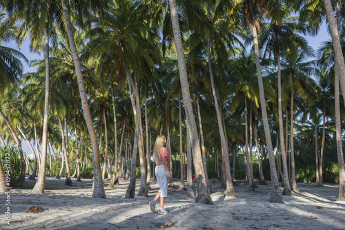 Young beautiful woman is walking in a rainforest among palm trees photo