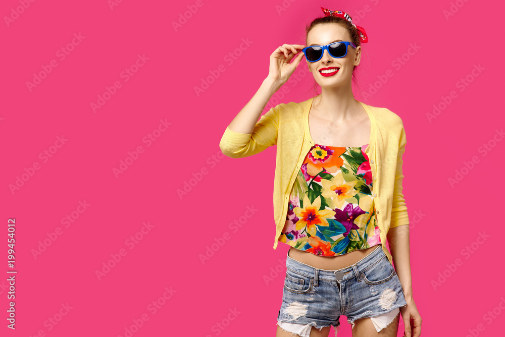 Young beautiful girl in a yellow sweater and sunglasses on a pink background laughing. Colour obsession concept. Minimalistic style. Stylish Trendy Young beautiful girl in a yellow sweater and sunglasses on a pink background laughing. Colour obsession concept. Minimalistic style. Stylish Trendy