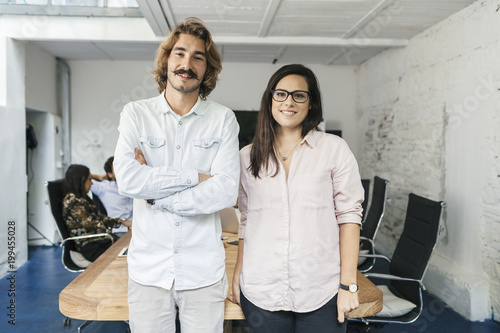 Startup of enterprise. Young business couple looking the camera and smiling during a meeting work in office