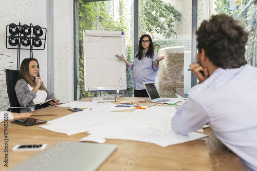 Young pregnant woman at work with his associates in the office during a meeting