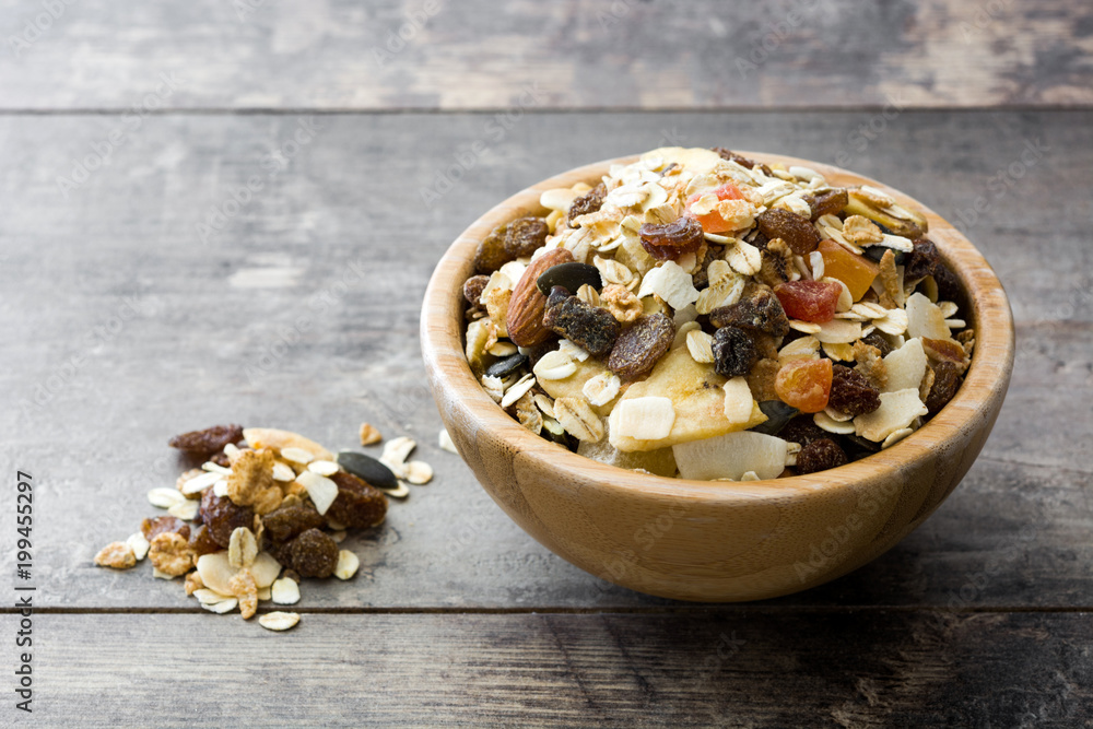 Muesli and dried fruit in wooden bowl on wooden table.  - obrazy, fototapety, plakaty 
