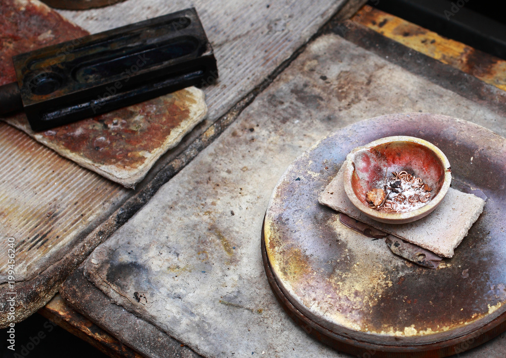 The workplace of a jeweller. In the bowl are pieces of gold for smelting.