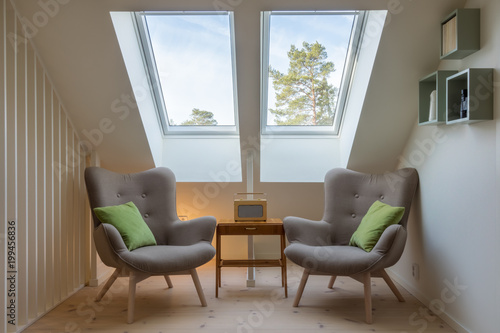 Modern retro design in a attic / loft. Small vintage table with a radio on and two reading chairs under two skylights. photo