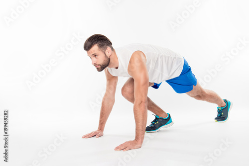 Fullbody, full-length half turned portrait of strong, professional, successful, athletic, confident, sporty, active guy is ready for start running, isolated on white background