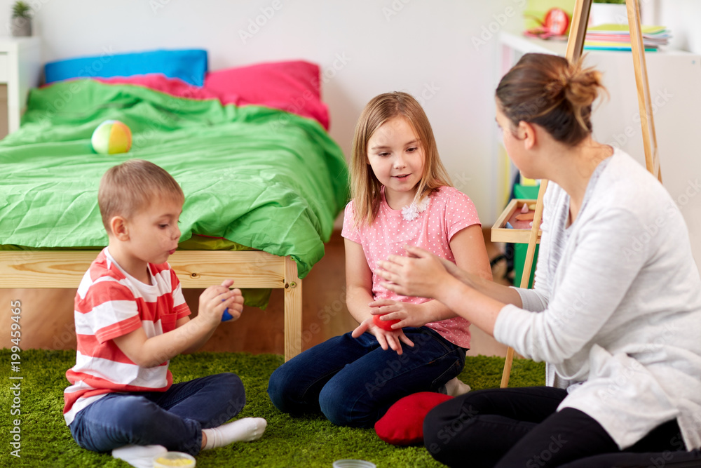 childhood, leisure and people concept - group of happy kids and and mother with modelling clay or slimes at home childhood, leisure and people concept - group of happy kids and and mother with modelling clay or slimes at home
