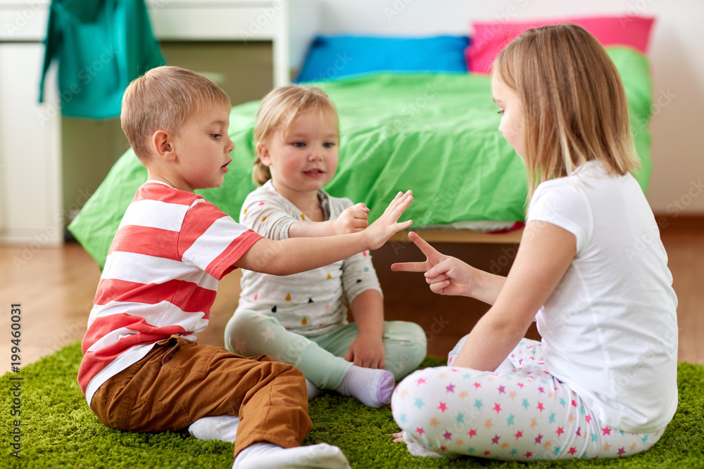 childhood, leisure and family concept - happy little kids playing rock-paper-scissors game at home childhood, leisure and family concept - happy little kids playing rock-paper-scissors game at home