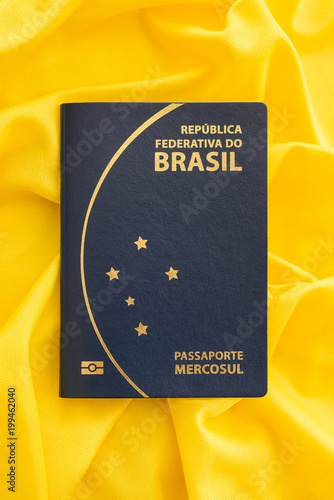 Brazilian passport on yellow fabric representing the Brazilian flag. Important document for trips abroad.