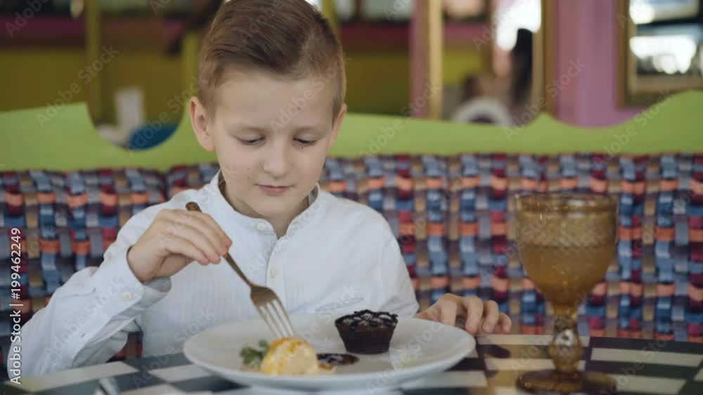 Handsome smiling boy starts to eat a tasty dessert in cafe. 4K Handsome smiling boy starts to eat a tasty dessert in cafe. 4K