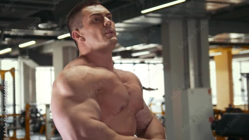 Strong muscular shirtless man in front of mirror in a gym Strong muscular shirtless man in front of mirror in a gym