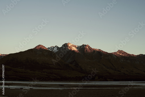 Paisaje de picos de montañas nevadas con cielo azul despejado al atardecer en Nueva Zelanda	