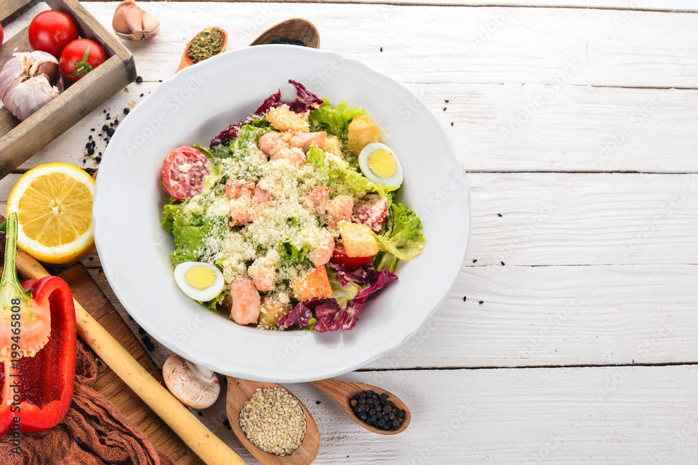 Caesar salad with salmon. Fresh vegetables. Healthy food. Top view. On a white wooden background. Copy space. Caesar salad with salmon. Fresh vegetables. Healthy food. Top view. On a white wooden background. Copy space.