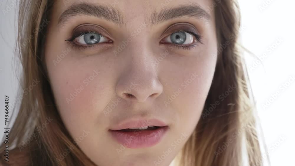 Young beautiful caucasian woman looking at camera, smiling, portrait, daylight, near window, curtain, close up 50 fps Young beautiful caucasian woman looking at camera, smiling, portrait, daylight, near window, curtain, close up 50 fps
