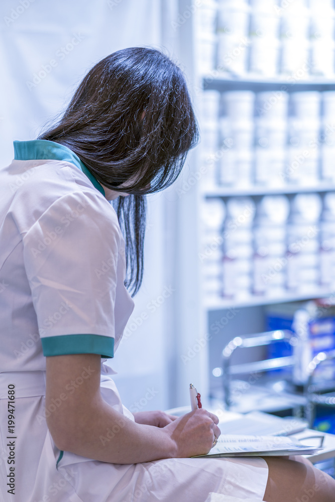 A nurse in a white coat writes something in the office A nurse in a white coat writes something in the office