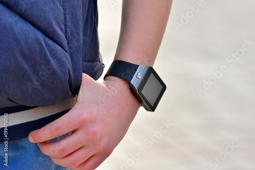 A smart watch on the boy's hand in a blue jacket with rolled up sleeves photo