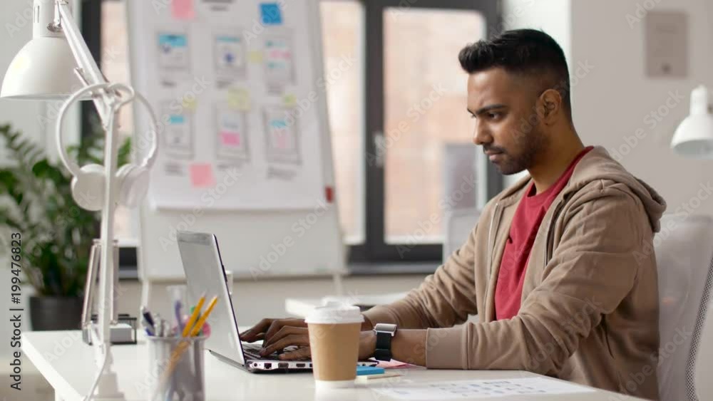 business and creative people concept - young indian man with laptop computer working at office