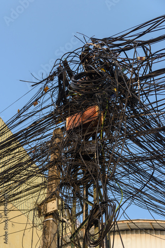 Electricity pole with dozens of dangerous untidy messy cables and wires photo