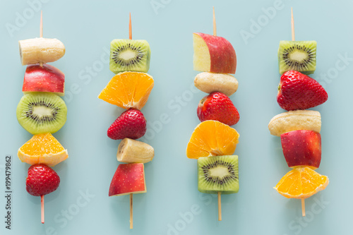Fototapeta Naklejka Na Ścianę i Meble -  fruit skewers the concept of healthy eating / pastel turquoise glass background.