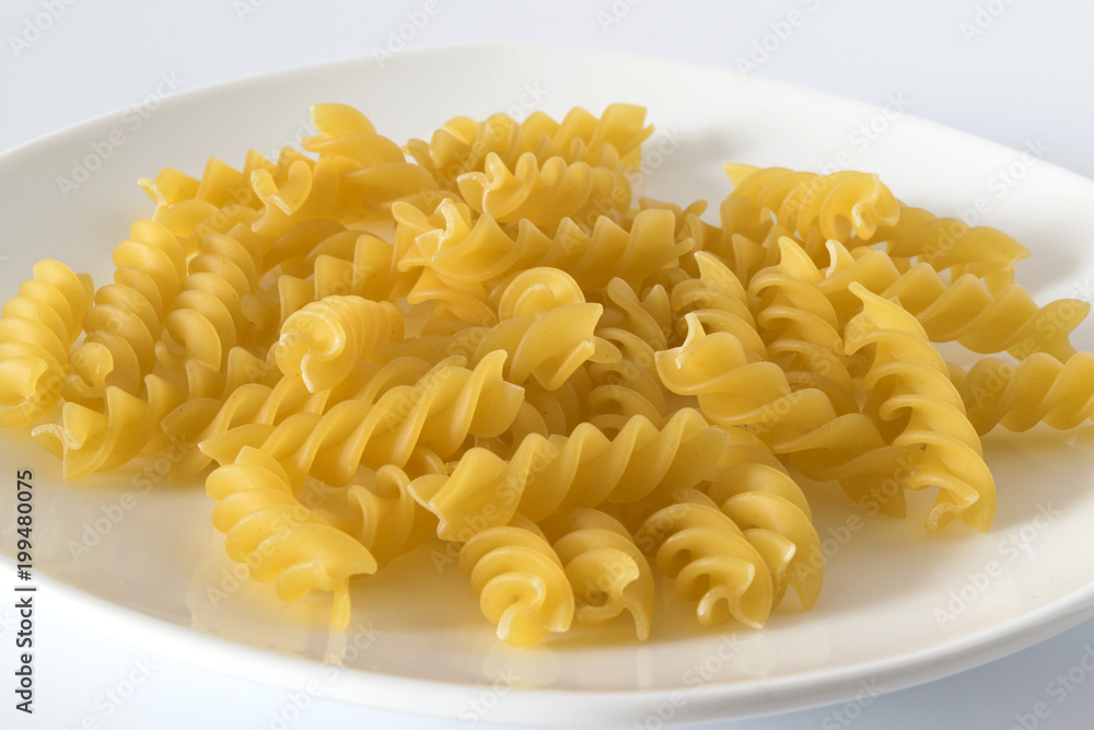 Uncooked spiral pasta on a white plate. Macro Uncooked spiral pasta on a white plate. Macro