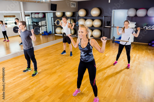 Fototapeta Naklejka Na Ścianę i Meble -  Focused team doing squat exercises with weights at fitness gym