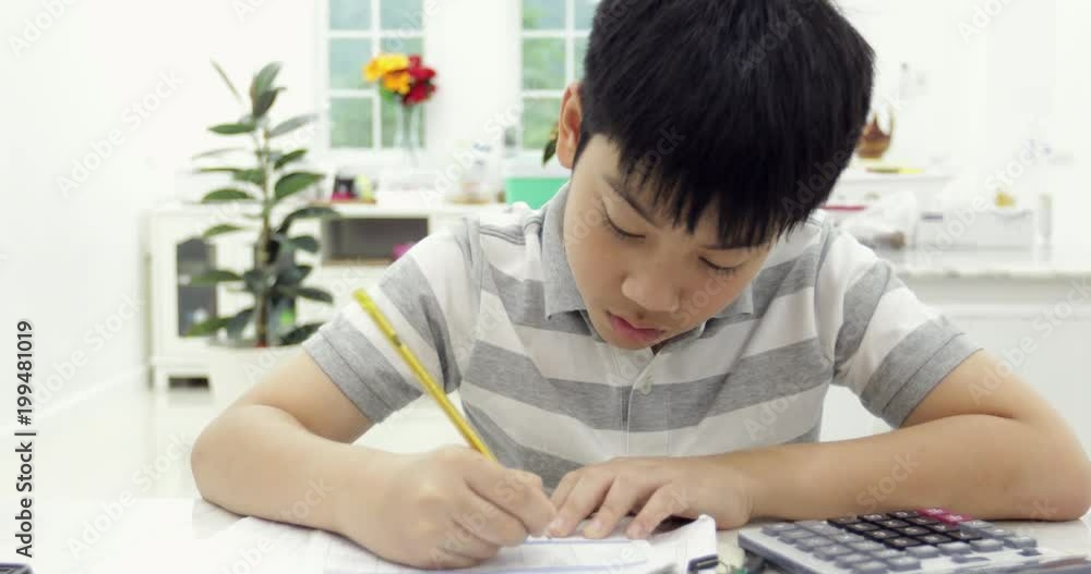 Asian child reading calculating and writing to do homework at home. Asian child reading calculating and writing to do homework at home.
