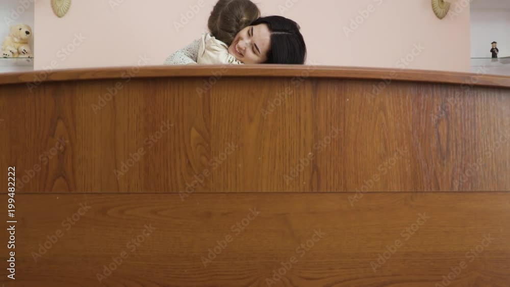 Young mother hugs her daughter sitting on the bed Young mother hugs her daughter sitting on the bed