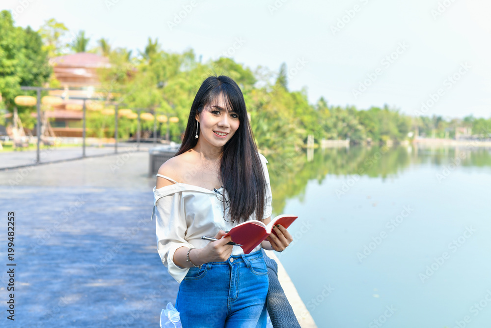 Education Concepts. Asian women reading books in the park. Beautiful women are relaxing in the park. Beautiful women are happy to read.