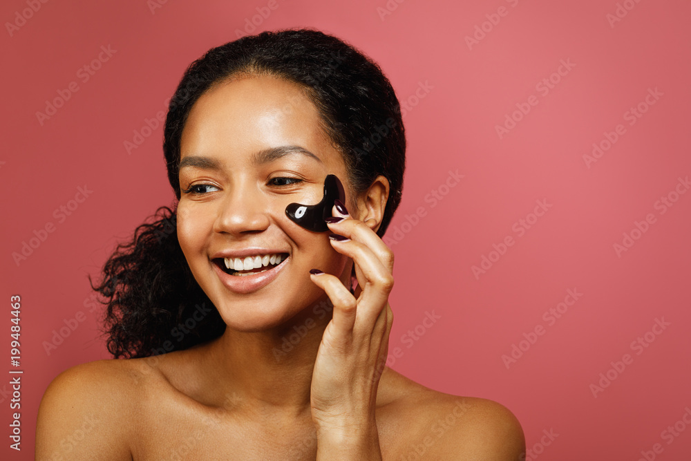 Happy woman applying face patch with hand, copy space Happy woman applying face patch with hand, copy space