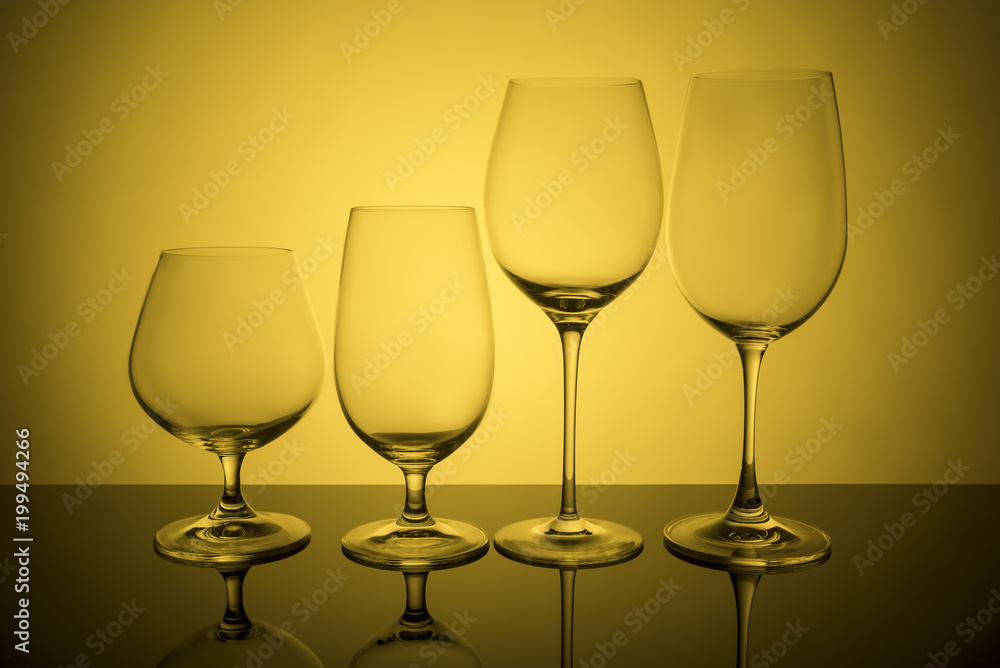 Glass glasses stand in a row on a yellow background.