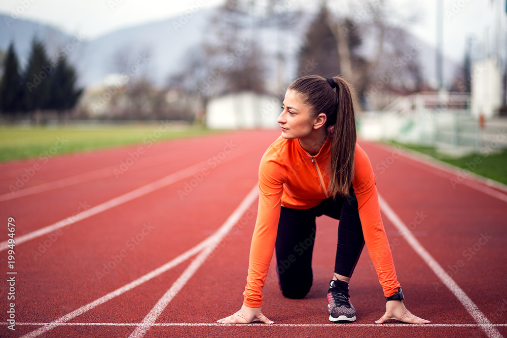 Fototapeta premium Female athlete in starting position ready for running