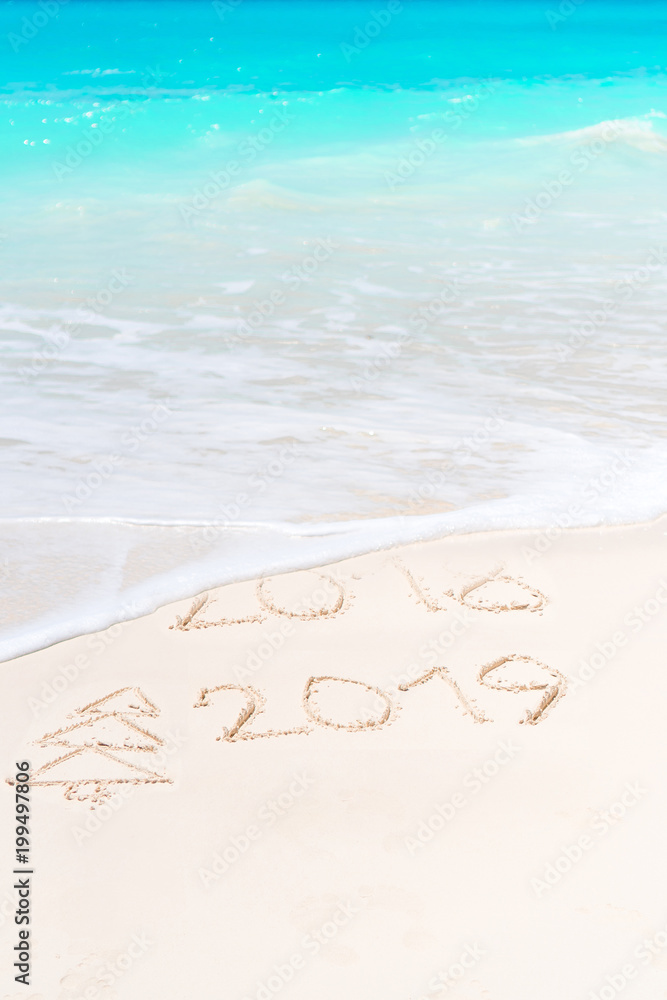 Fototapeta premium 2018 and 2019 handwritten on sandy beach with soft ocean wave on background